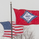 In a February 2011 file photo, the U.S. and Arkansas flags blow in the wind in Fayetteville, Ark. Arkansas has decided to remove two Confederate-era statues representing it in Statuary Hall, but the state still has refused to change the meaning of a star on the state’s flag that currently represents the Confederacy.